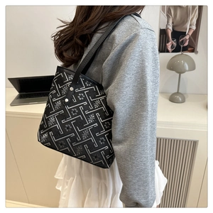 Dettaglio di ricami floreali su una borsa a secchiello nera minimalista con tracolla fine