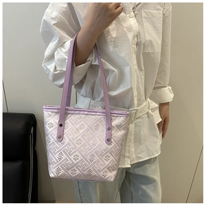 Dettaglio ravvicinato di una borsa a secchiello ricamata viola con manici in pelle