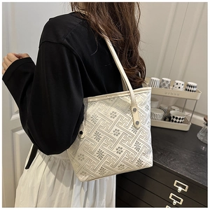 Dettaglio della borsa tote crema con motivi geometrici e rivetti sulla tracolla a spalla