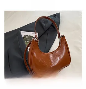 Détail d'un sac hobo en cuir froissé marron brillant avec une forme demi-lune chic