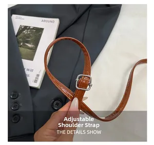 Détail de la bandoulière réglable en cuir marron effet croco avec boucle argentée élégante