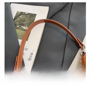 Détail de la bandoulière en cuir marron avec coutures fines et ferrures argentées