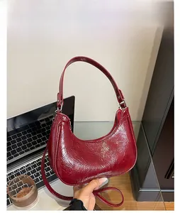 Gros plan sur la texture en cuir plissé rouge foncé d'un sac à main en demi-lune
