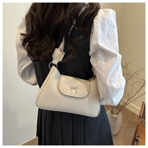 Elegante borsa a tracolla beige con fiocco in metallo indossata da una modella in interno