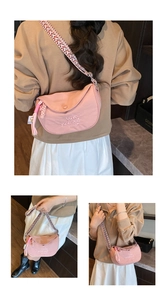 Close-up of pink crescent bag with white Love Yourself embroidery and woven strap
