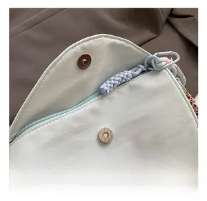 Detail of light blue shoulder bag featuring magnetic buckle and Love Yourself embroidery