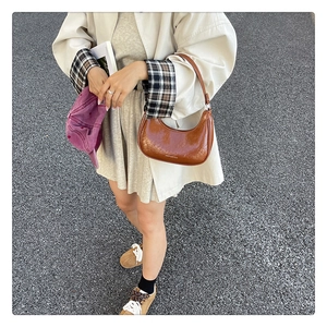 Sac hobo en cuir marron porté avec un trench beige et un look streetwear décontracté