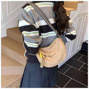 Detail of beige half-moon crossbody bag with wide ethnic strap and fringe charm