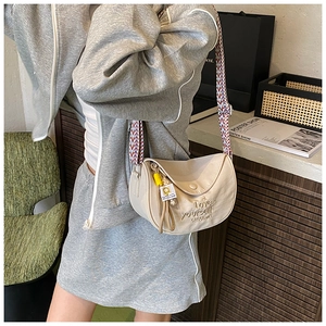 Detail of beige crescent shoulder bag with colorful woven strap and embroidery