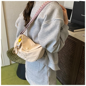 Detail of cream crossbody bag featuring ethnic woven strap and Love yourself embroidery