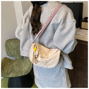 Detail of creamy crescent bag with woven strap and Love yourself embroidery