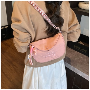Detail of pink semi-circular crossbody bag with embroidered slogan and woven strap