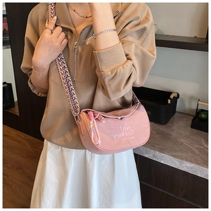 Close-up of pink crescent crossbody bag with Love yourself embroidery and woven strap