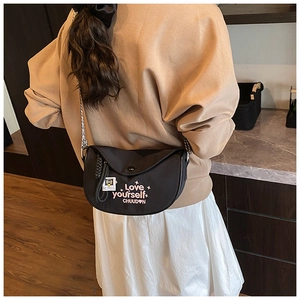 Detail of black crescent crossbody bag with embroidery and silver metal chain strap