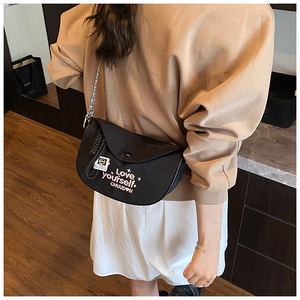 Detail of black crescent crossbody bag featuring Love yourself embroidery and chain strap