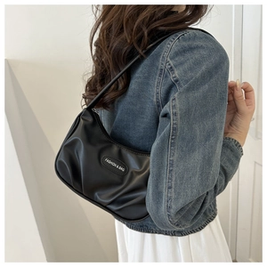 Détail d'un sac sous le bras noir plissé avec logo moderne et fermeture à glissière