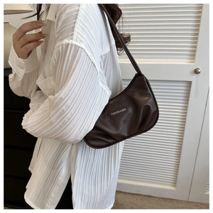 Detail of a dark brown pleated underarm bag showing the fashion label and soft texture
