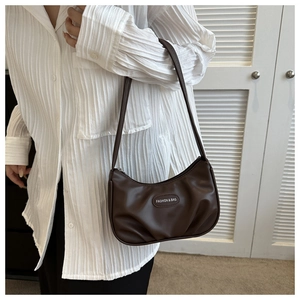Detailed view of the brown ruched crescent bag on shoulder with a white pleated shirt