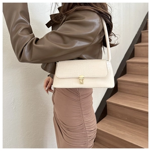 Detail of cream white croc-embossed shoulder bag with golden buckle on a fashion model
