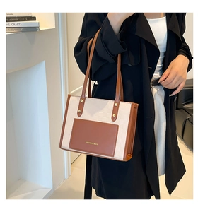 Détail du sac cabas bicolore avec rivets métalliques et lettrage doré à la mode