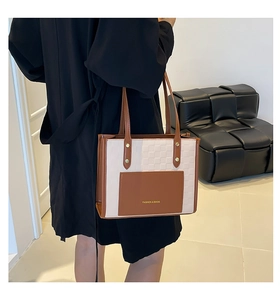 Détail du sac cabas beige et marron avec texture tissée et poche à slogan mode
