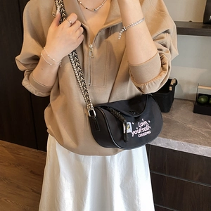 Black crescent crossbody bag with Love yourself print and woven strap on model