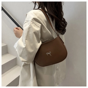 Brown half-moon shoulder bag featuring a vintage silver bow accent shown on model