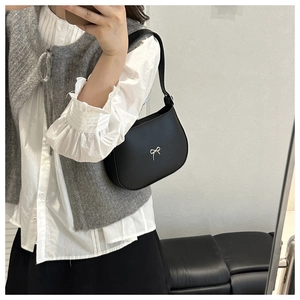 Mirror selfie showing the scale of a black crescent shoulder bag with silver bow detail