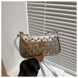 Detail of silver metallic crossbody bag with studs and pink star on quilted surface
