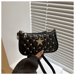 Close-up of black patent leather crossbody bag with silver rhinestone star and quilted texture
