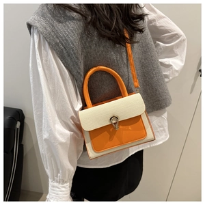 Detail of a chic orange and beige two-tone mini handbag with silver U-shaped metal clasp