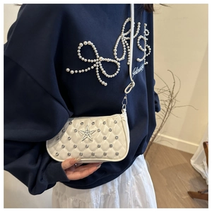 Close-up of white quilted crossbody bag with silver star and rhinestone details