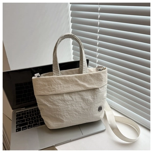 Close-up of cream nylon bucket bag with crinkle texture placed on a silver laptop