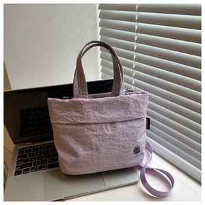 Detail of lavender textured tote bag with pleated fabric and brand woven label