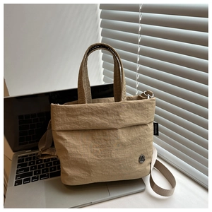 Detail of khaki nylon bucket bag with metal logo and woven strap on laptop