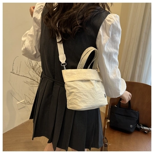 Detail showing white pleated texture bucket bag with logo and matching shoulder strap