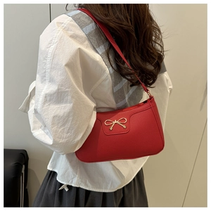 Detail of red pebbled leather shoulder bag with elegant metal bow ornament