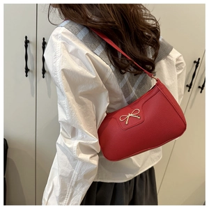 Detail view of red bow knot underarm bag with lychee texture and golden buckle