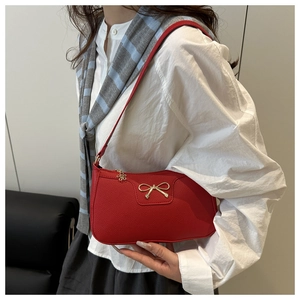 Detail of red leather handbag with gold bow ornament and flower zipper charm
