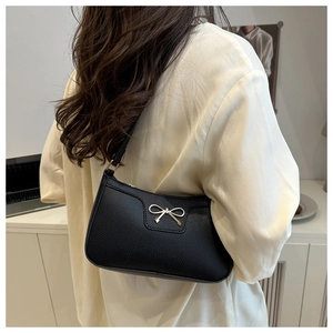 Detail of the golden bow clasp on the black lychee pattern leather shoulder bag