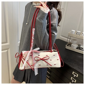 Detail of red bow patterns and lace trim on a canvas underarm bag with double straps