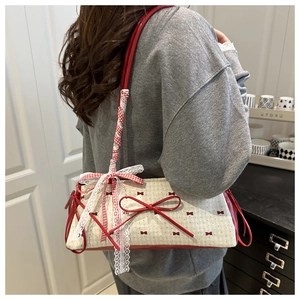 Close-up of beige polka dot shoulder bag featuring lace details and a red bow accent