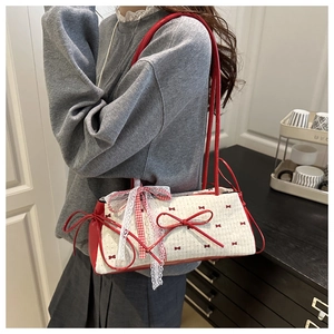 Model carrying a red and white bow print underarm bag with decorative leather accents