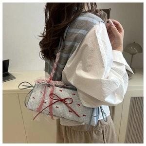 Detail of red bow and lace trim on a light blue checkered canvas shoulder bag