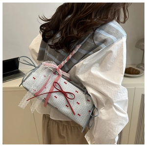 Detail of blue plaid canvas bag featuring red bows and delicate white lace trim edges