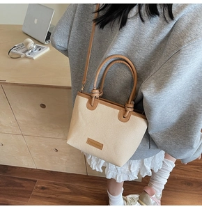 Detailed close-up of the beige woven texture and leather knot handle on the bucket bag