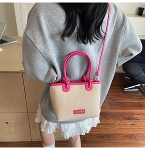 Detail of beige woven bucket bag with pink leather trim and knot handle design