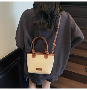 Detail of the woven canvas bucket bag featuring a knot handle and leather fashion label