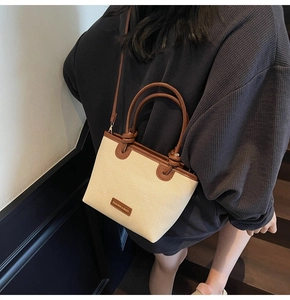 Detail of woven bucket bag featuring brown leather trim and knotted handle detail
