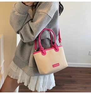 Detail of the pink leather handles and branded tag on the woven straw bucket bag